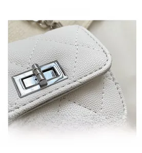 Detailed macro view of white quilted leather cross-body bag with silver metal turn-lock
