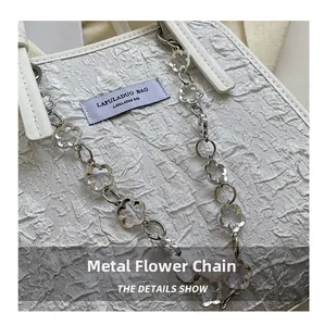 Détail du sac plissé blanc avec sa chaîne métallique florale et son tissu texturé