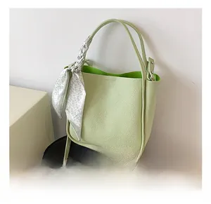 Green lychee pattern leather bucket bag detail with floral scarf on a black chair