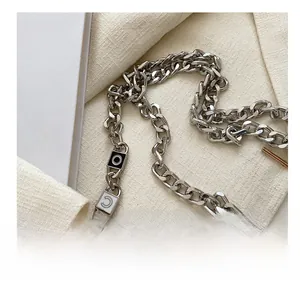 Detail of silver chain strap with black and white accents on a white quilted handbag