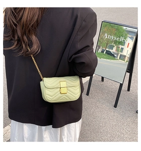 Outdoor street view of a mint green quilted chain bag worn over a black blazer
