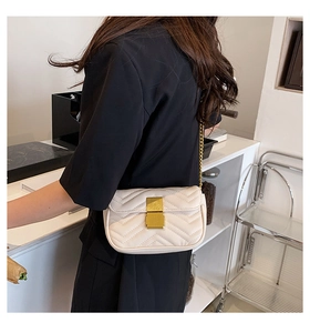Detail of cream quilted shoulder bag featuring gold chain strap and rectangular clasp