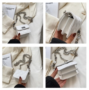 Detail view of white quilted crossbody bag with silver twist lock and chain strap