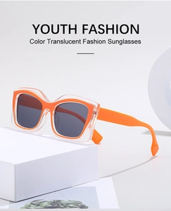 Detail of trendy orange cat-eye sunglasses with translucent frames on a white block