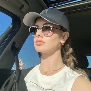 Close-up of retro cat-eye sunglasses with gradient lenses worn by a model in a car