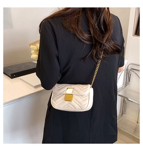 Detail of cream quilted crossbody bag with gold chain strap and elegant rectangular lock