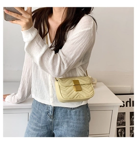 Close-up of cream quilted crossbody bag with golden lock and chain strap on model
