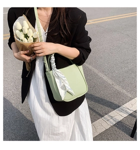 Close-up of mint green bucket bag with floral silk scarf detail and long shoulder strap