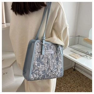 Détail du cabas bleu clair avec tissu texturé argenté et accessoire chaîne à fleurs