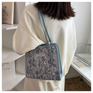 Détail du sac à bandoulière en tissu floral avec bordure en cuir bleu clair et chaîne