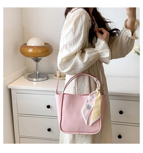 Pink lychee grain bucket bag with a decorative star pattern silk scarf on the handle