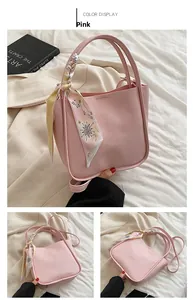 Detail of pink pebbled leather bucket bag featuring a decorative star pattern scarf on handle