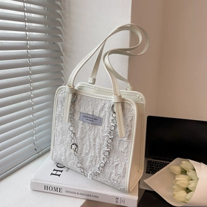 Sac fourre-tout crème texturé avec chaîne fleurie argentée et poignée en cuir en scène de vie