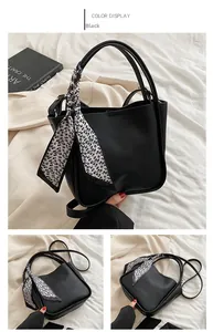 Detail view of a black pebble leather bucket bag featuring a decorative floral silk scarf handle