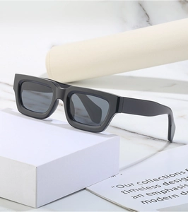 Detailed side view of vintage black square steampunk sunglasses on a white geometric stand