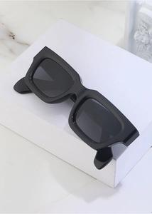 Detail shot of black rectangle sunglasses with matte frames on a white geometric block