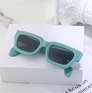 Detail view of mint green steampunk rectangular sunglasses with dark lenses on a pedestal