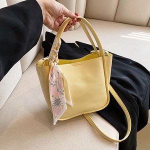 Chic yellow lychee leather bucket bag with decorative silk scarf and cross-body strap