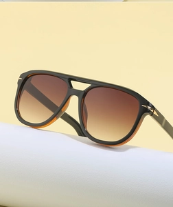 Detail of pilot sunglasses showing double-bridge frame and golden T-shaped metal hinges