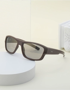 Détail de lunettes de soleil Y2K marron à monture large avec rivets sur socle blanc