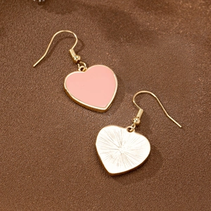 Boucles d'oreilles cœur en or avec émail rose sur un fond brun texturé