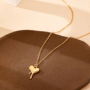Polished gold heart pendant necklace with melting liquid design on minimalist display