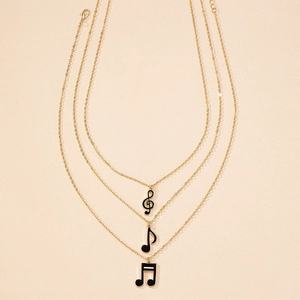 Detailed close-up of triple-layered gold musical note pendants with black enamel coating