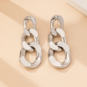 Macro detail of silver link earrings with polished finish on a textured background