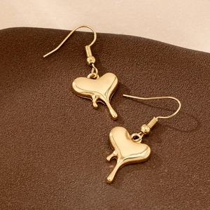 Elegant gold molten heart dangle earrings with fluid teardrop design on dark leather