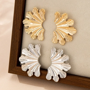 Macro view of textured leaf earrings in gold and silver finish with radial fold details