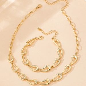 Détail de parure collier et bracelet dorés avec maillons en forme de gouttes