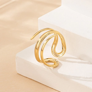 Close-up of golden triple-layered spiral ring on a minimalist stone display