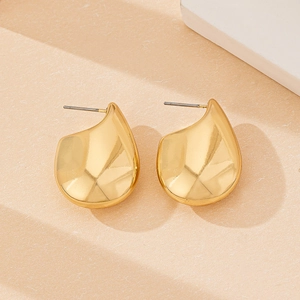 Macro shot of polished gold water drop earrings with stainless steel posts on stone