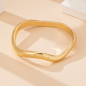 Macro shot of gold wavy irregular bracelet with highly polished finish and minimal style