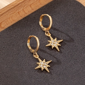 Elegant gold eight-point star earrings with clear crystal stones on black textured base