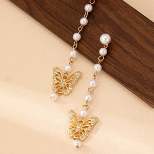 Elegante lange Quastenohrringe mit goldenen Schmetterlingen und Perlen auf Holzblöcken