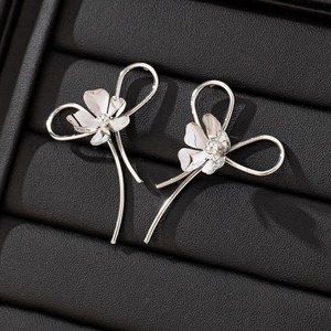 Minimalist silver flower stud earrings with elegant curved lines on black leather background