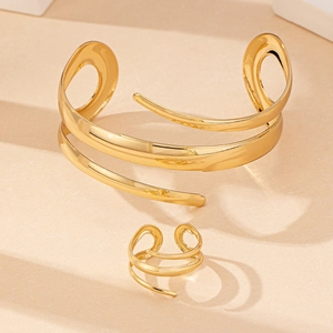Detailed view of hollow teardrop gold bracelet and ring set on geometric display