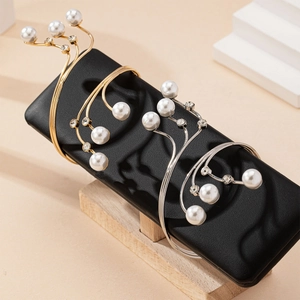 Elegant gold and silver branch-style cuff bracelets with pearls and crystals on stand