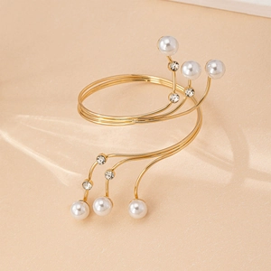 Detail of golden spiral arm cuff with white pearls and sparkling rhinestones