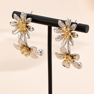 Elegant vintage silver daisy flower earrings with gold center on a display stand