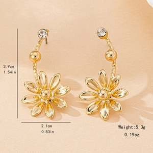 Elegant gold flower drop earrings with crystal studs on textured beige surface