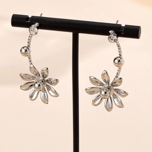 Elegant silver daisy flower drop earrings with clear zircon on a black metal display