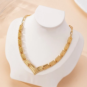 Elegante goldfarbene geometrische V-Halskette mit Perlenstruktur auf einem Schmuckständer