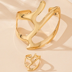 Close-up of golden irregular cutout bracelet and matching ring set with high polish finish