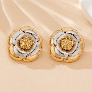 Gros plan d'élégantes boucles d'oreilles camélia bicolores avec pétales métalliques
