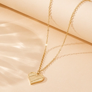 Collier élégant avec pendentif cœur doré à texture mate et lignes géométriques
