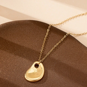 Elegant gold necklace with hammered water drop pendant on a minimalist display stand