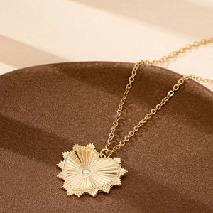 Elegant gold heart pendant necklace with sunburst texture and white gemstone for women