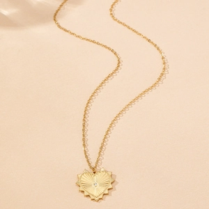 Macro shot of gold heart pendant featuring radiant sunray texture and center zircon stone